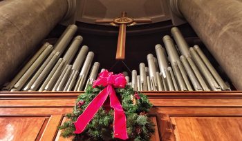 Pipe organ pipes with a Christmas wreath and red bow. Low angle view.